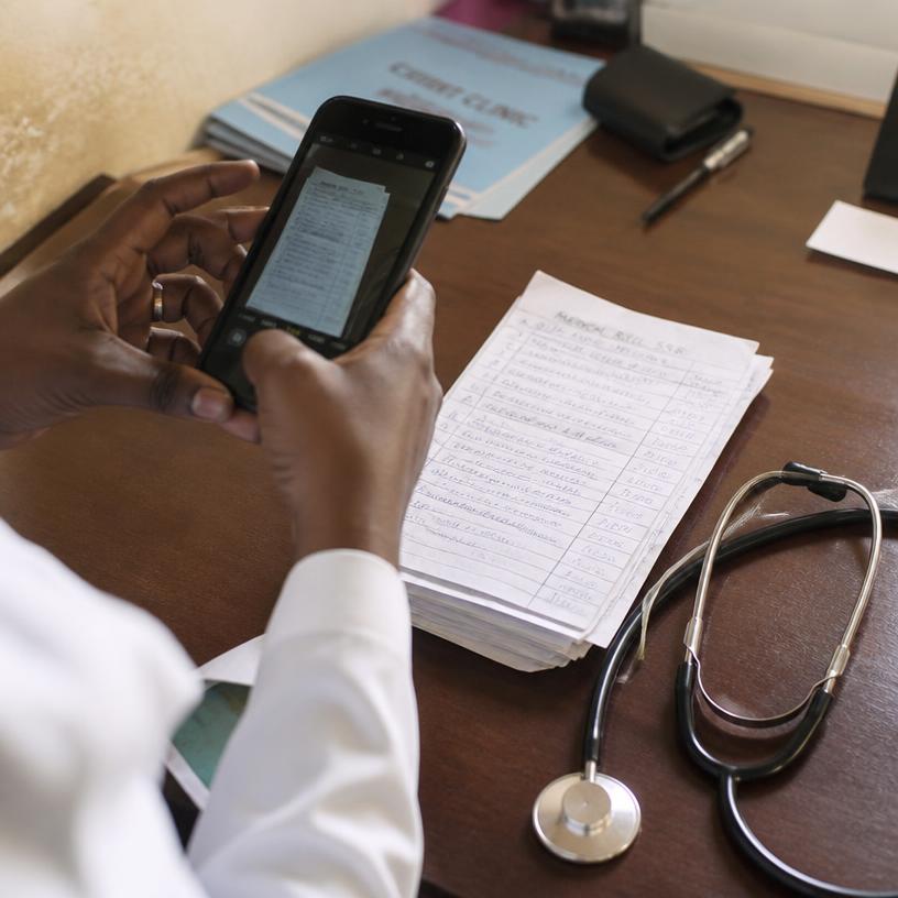 A clinician photographing a stack of handwritten bills with a phone